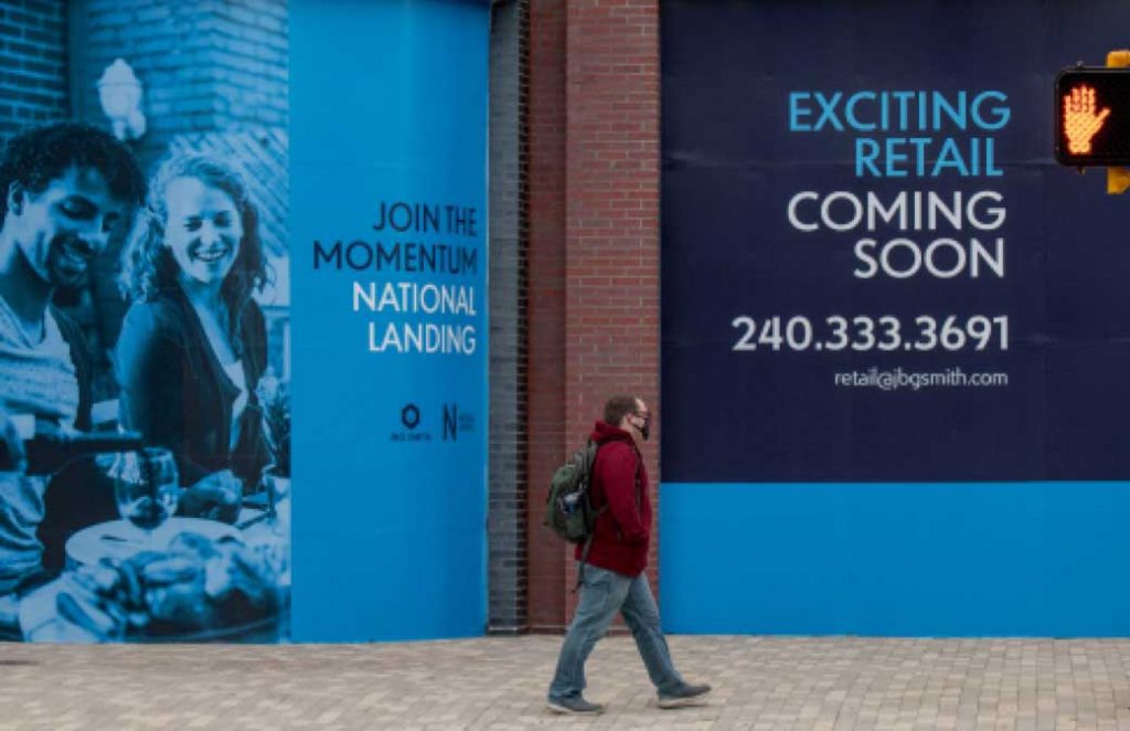 man walking in front of National Landing coming soon signage